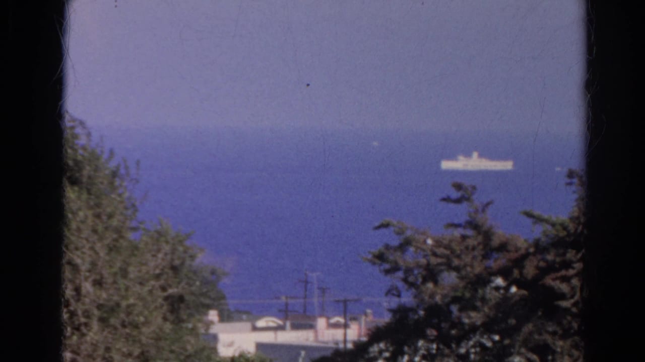 1966 Silver Lake view toward blue water with a small white ship in the distance and trees and rooftops in the foreground.