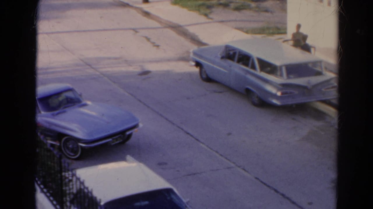 The blue convertible begins pulling out on a Silver Lake residential street, framed by dark vertical window bars.