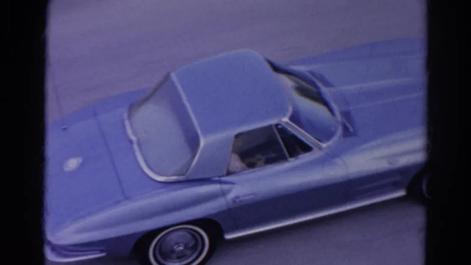 1966 Silver Lake home-movie frame showing a light blue classic sports car from an elevated angle, with film borders and soft 8mm color.