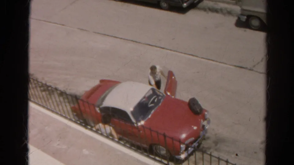 A man opens the door of a red and white two-tone car in 1966 Silver Lake home-movie footage.