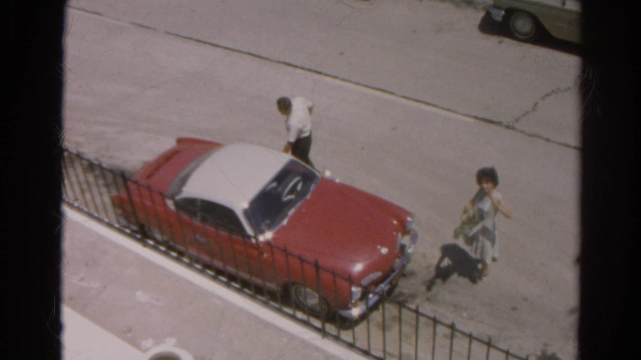 The elevated 1966 Silver Lake view shows the man by the parked red car as the woman moves along the street with a small object or package.