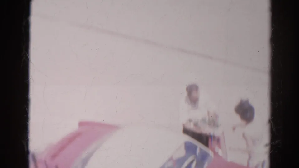In 1966 Silver Lake footage, adults appear near a red and white car, with soft focus and visible 8mm frame edges.