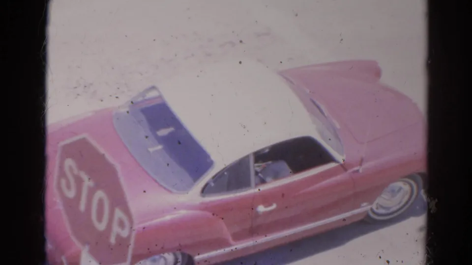 1966 Silver Lake frame showing the rear side of a red and white car beside a visible stop sign marking.