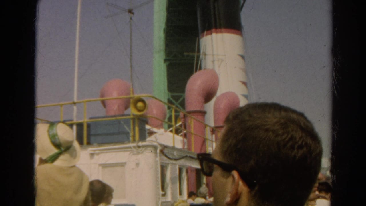 1966 8mm frame of people watching a docked ocean liner with pink funnels, yellow railings, and a black-and-white smokestack.