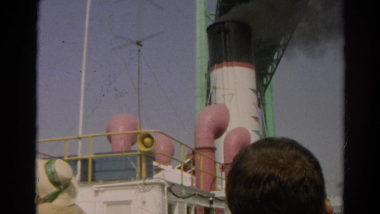 Ship smokestack and deck vents under a green structure, with a man's head in the foreground.