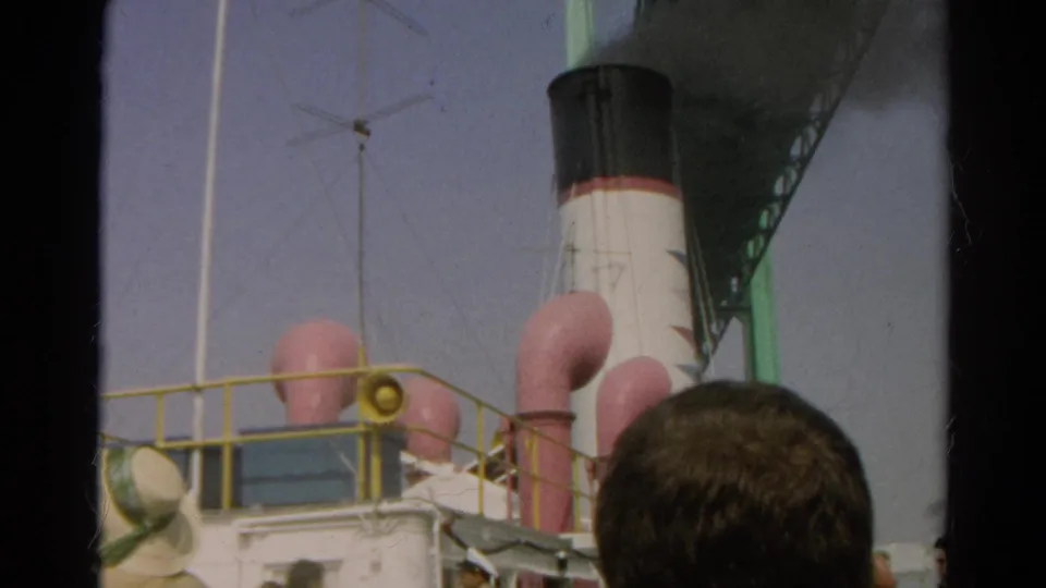 The final frame keeps the vessel's smoking stack, pink deck vents, yellow railing, and foreground spectator within the 1966 home-movie composition.