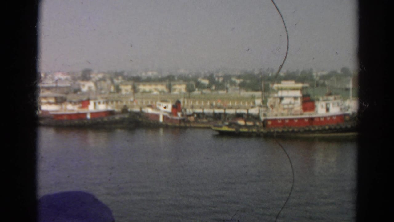 Tugboats and small work vessels moored beside a low industrial waterfront.