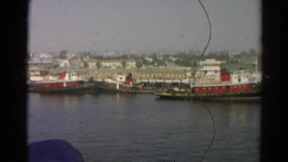 Listed 1966 Silver Lake harbor view with red and white tugboats, small vessels, water, and distant shore buildings.