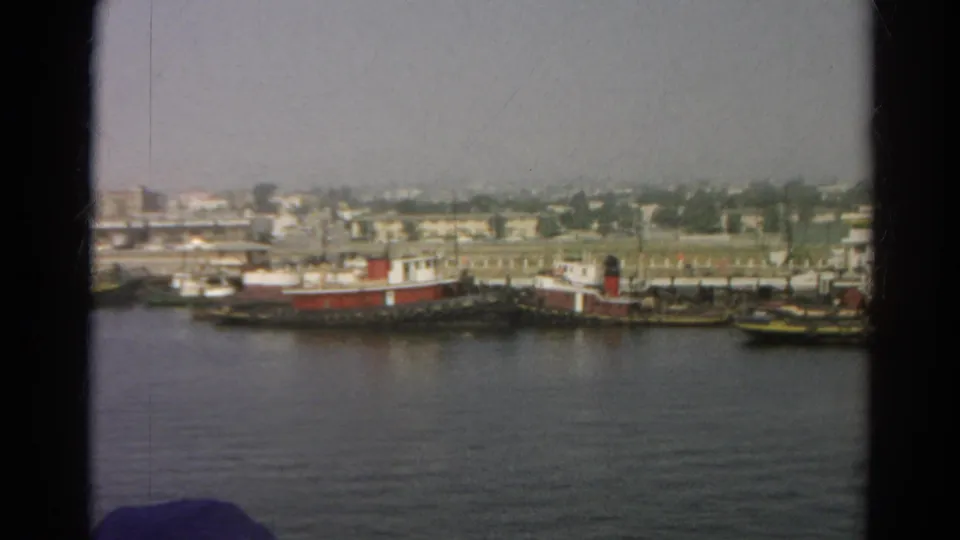 Final 1966 8mm frame of the listed Silver Lake harbor scene, with red tugboats moored across the water.