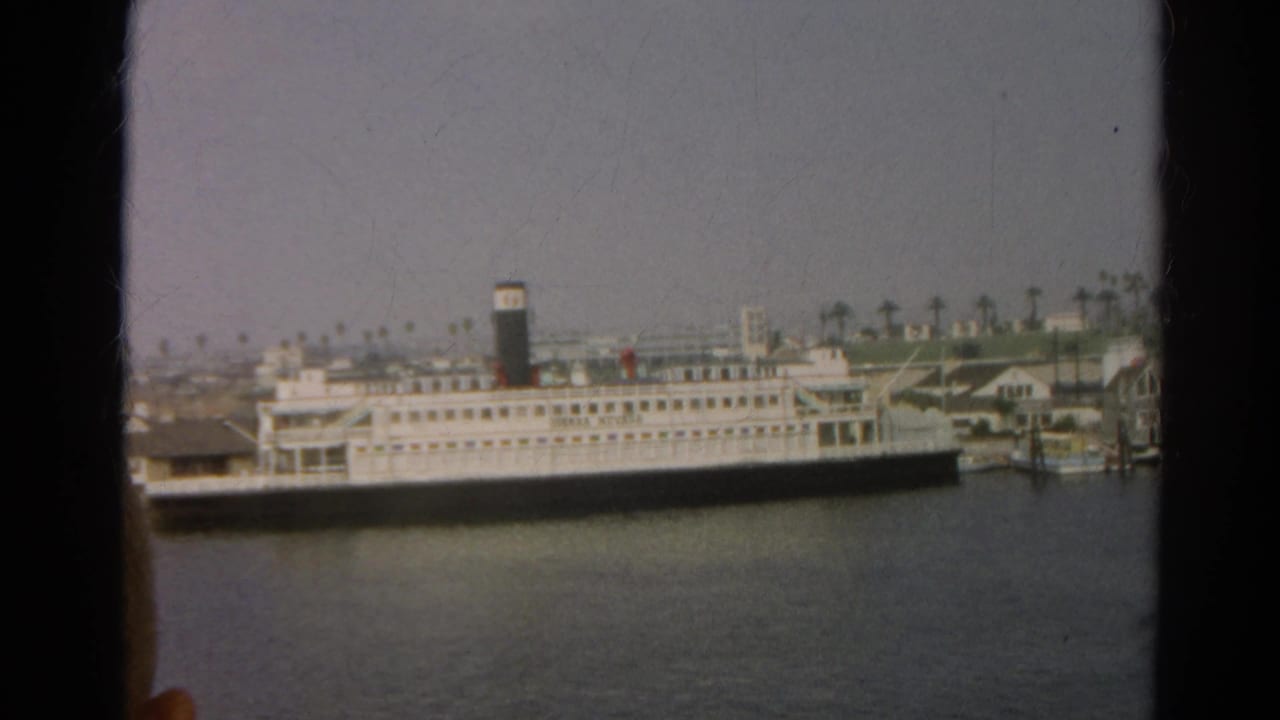 Reported 1966 California harbor view with a white passenger vessel, dark funnel, piers, and palm trees behind the waterfront.
