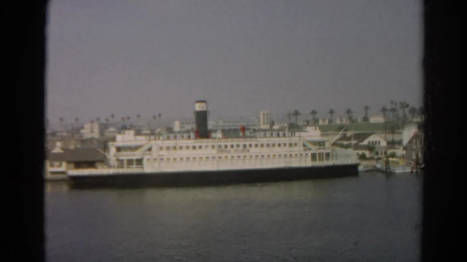 Soft 8mm frame of the reported 1966 Silver Lake, California harbor scene, showing a docked white ship across the water.