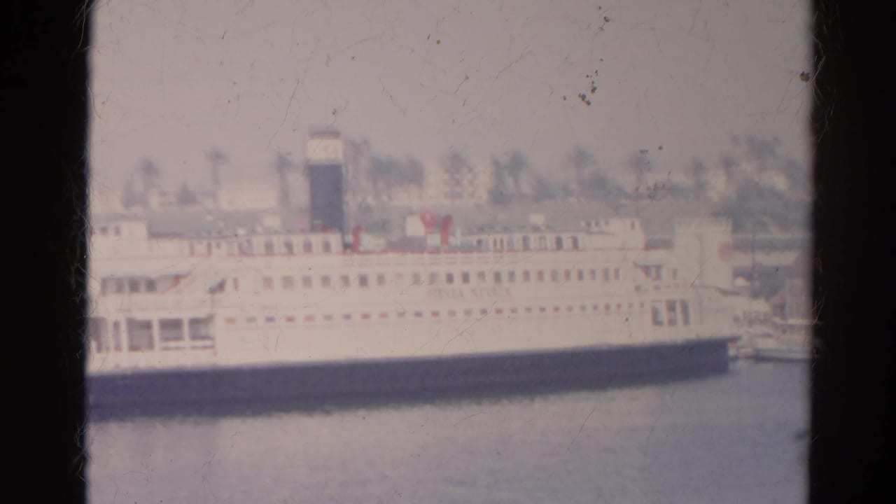 1966 8mm frame of a large white passenger boat docked in the listed Silver Lake, California waterfront setting.