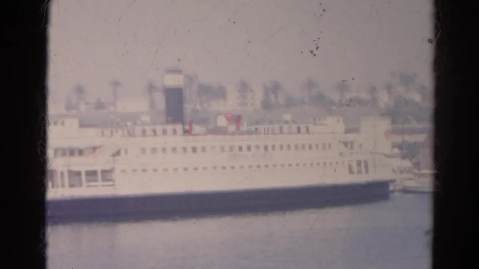 1966 8mm frame of a large white passenger boat docked in the listed Silver Lake, California waterfront setting.