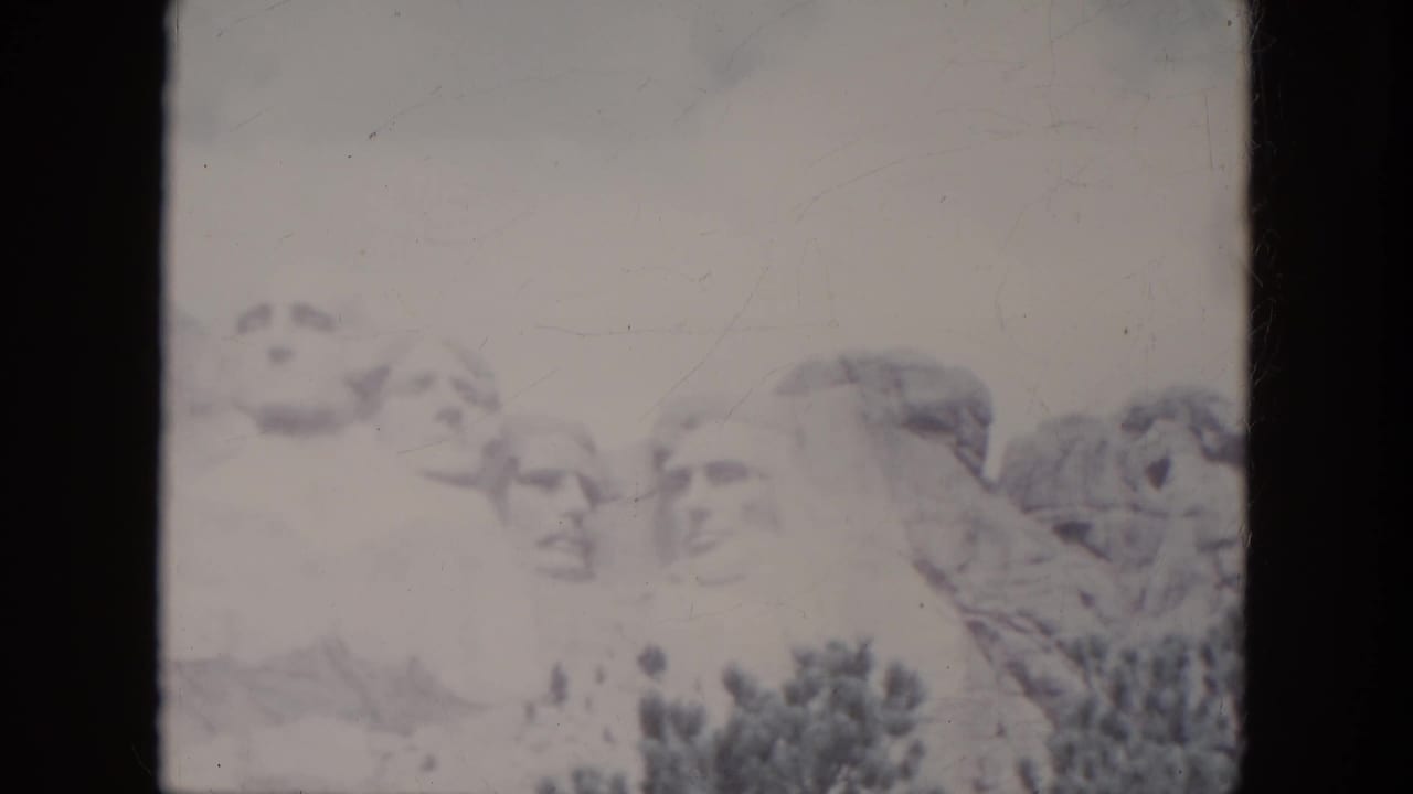 Faded 1966 8mm view of Mount Rushmore in South Dakota, with the carved presidential faces partly washed by exposure.