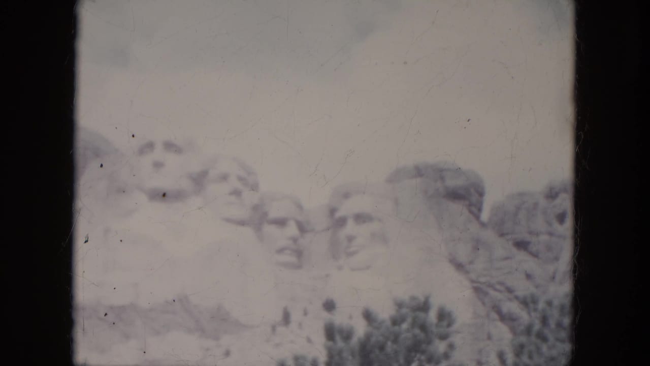 A second 1966 South Dakota home-movie frame shows Mount Rushmore with faded color, scratches, and dark frame borders.