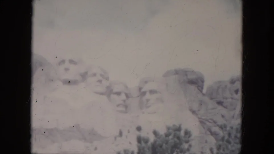 A second 1966 South Dakota home-movie frame shows Mount Rushmore with faded color, scratches, and dark frame borders.