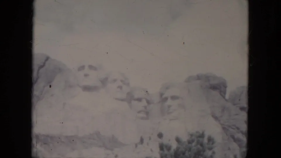 Overexposed 1966 8mm frame of Mount Rushmore, with the carved faces softened by faded color and film wear.