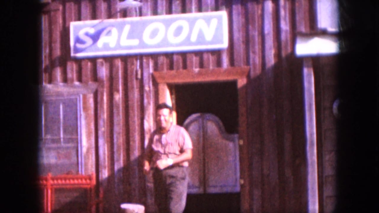 The man exits the western-style saloon facade, with swinging doors and the painted SALOON sign visible above.