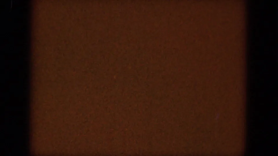 Opening 8mm frame with dark gate area and a partial South Dakota plains view under a cloudy sky.