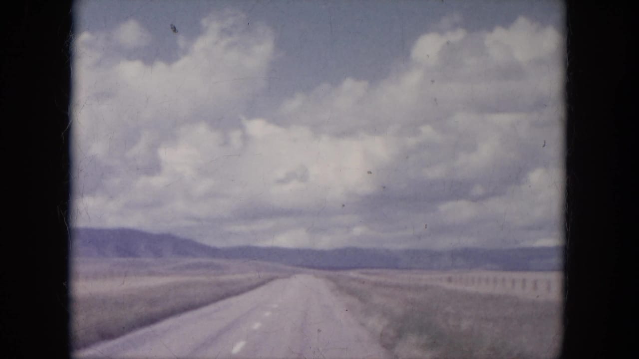 Straight rural road crossing open plains beneath a cloudy sky.