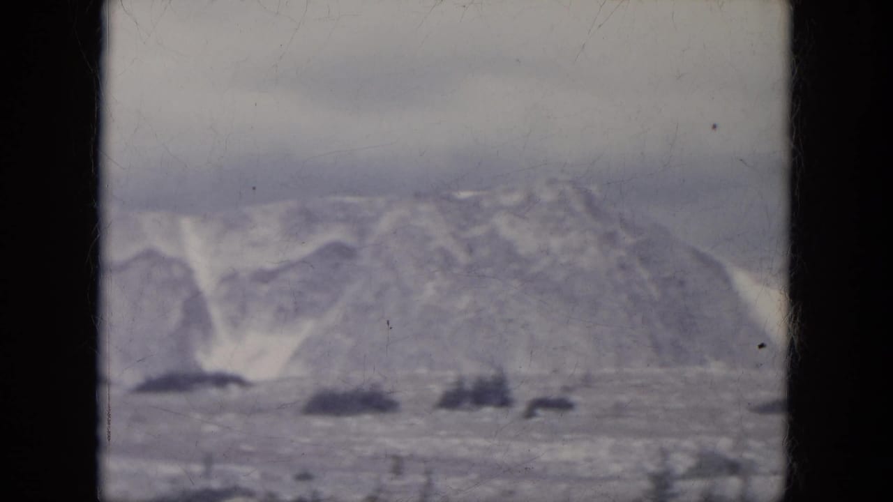 Snowy ridges and frozen open ground with several dark patches across the landscape.
