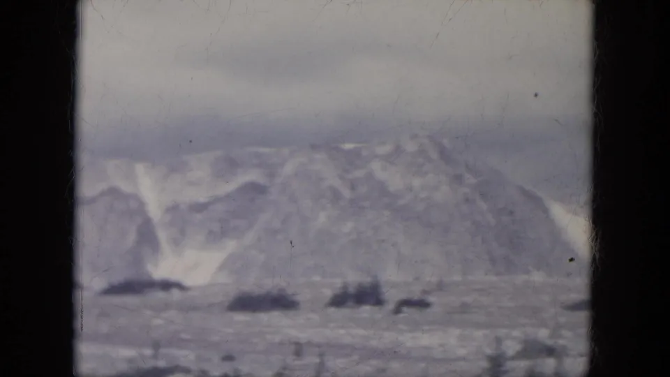 1966 South Dakota home-movie frame of snow-lined ridges and open frozen terrain, seen in soft focus on 8mm film.