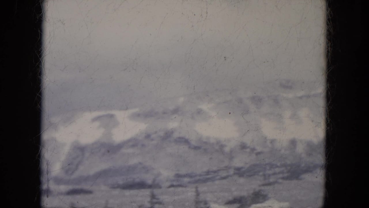 Snow-dusted hills beneath a pale sky, seen through a soft 8mm frame.