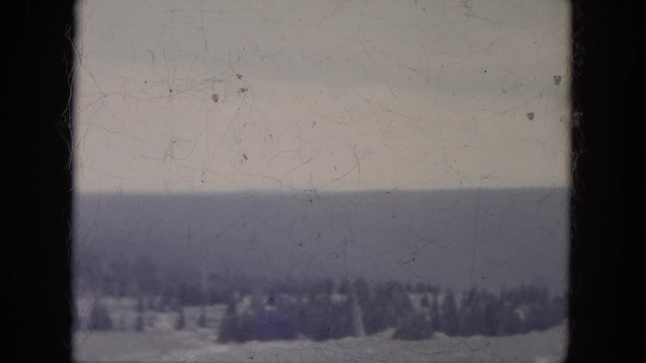1966 South Dakota 8mm frame showing a distant evergreen line across snowy terrain under a pale winter sky.