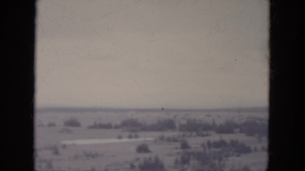 1966 South Dakota 8mm frame showing a hazy rural landscape with open fields and distant tree lines.