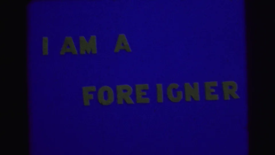 1967 Brazil 8mm-style title card with yellow block letters reading I AM A FOREIGNER on a blue field.