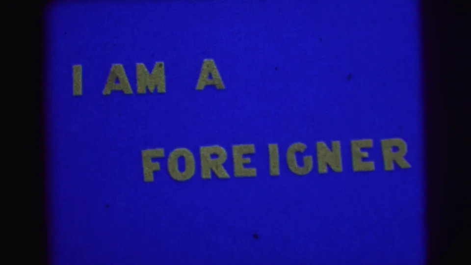 1967 Brazil archival frame with the phrase I AM A FOREIGNER in yellow letters on a blue 8mm title card.