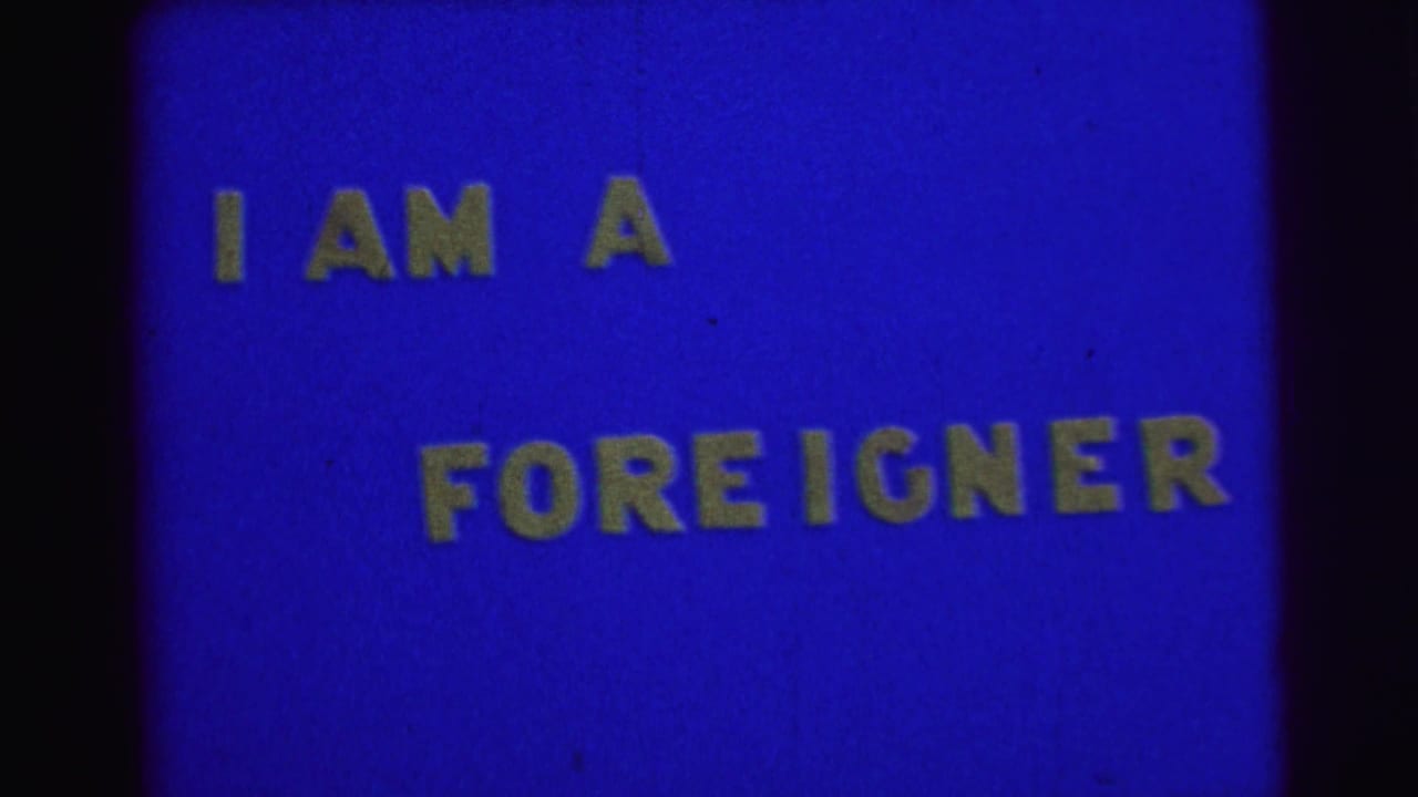 Blue title card with yellow block text reading I AM A FOREIGNER.