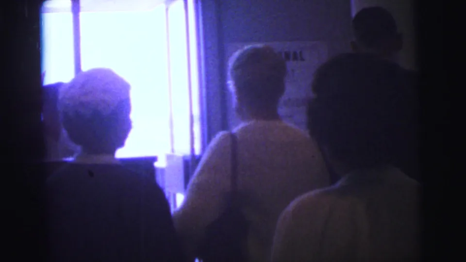 Silhouetted travelers in a Brazil airline-terminal interior face a bright doorway in this 1967 8mm frame.