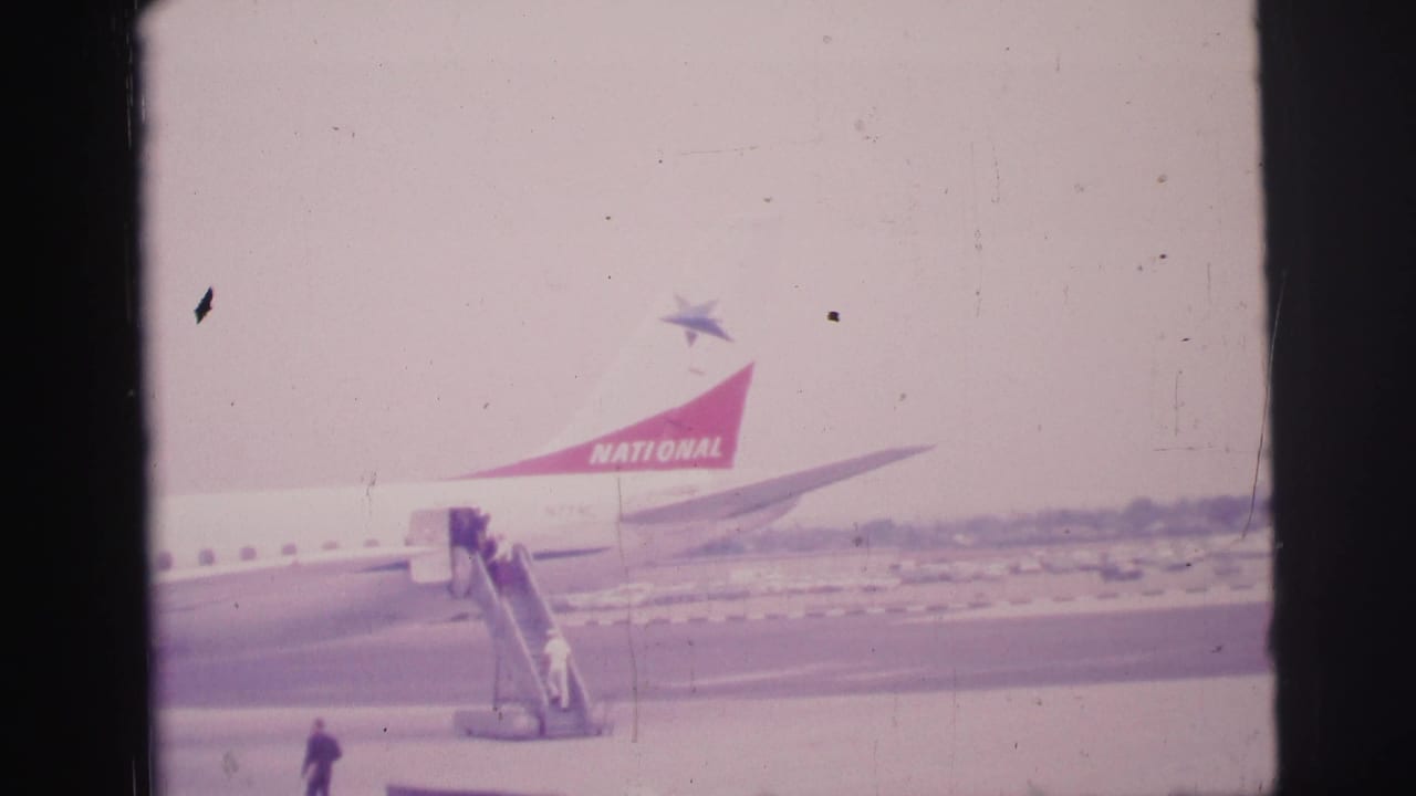 National Airlines aircraft tail and boarding stairs are seen across the tarmac.
