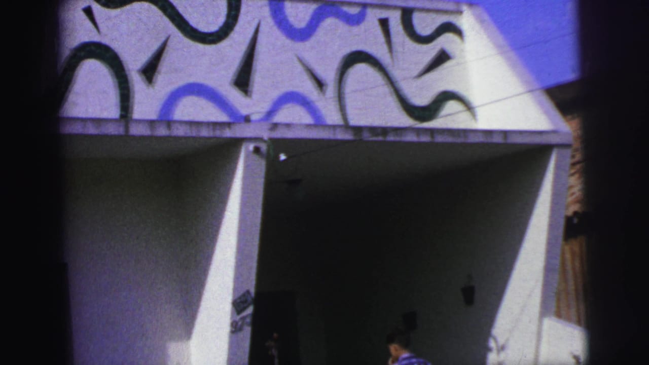White facade with blue and black geometric designs above a shadowed entrance.