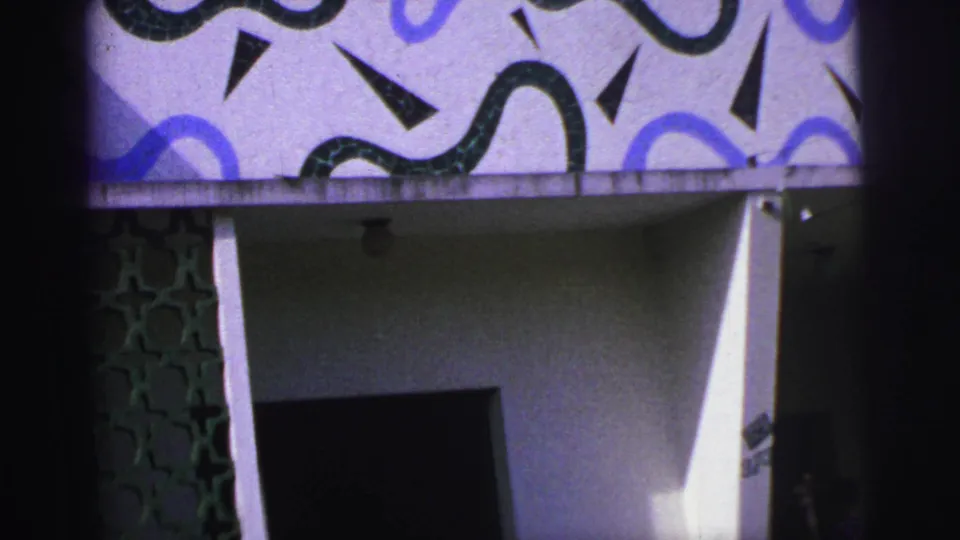 1967 Brazil 8mm frame showing geometric blue and black facade designs, a green lattice panel, and a dark recessed doorway.