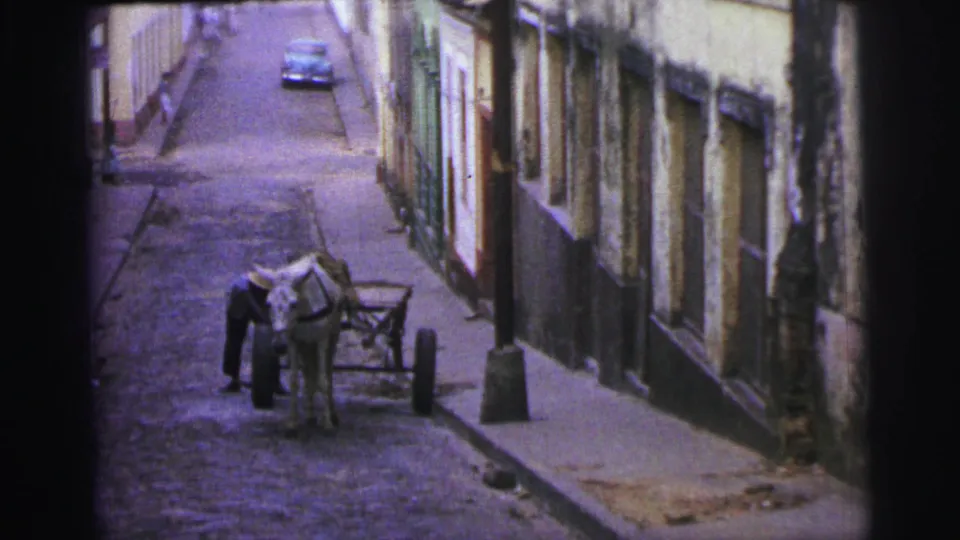 1967 Brazil street view with a horse-drawn cart near the curb, a man beside it, and a car in the distance.