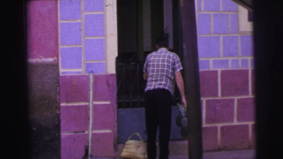 The final frame shows the man at the tiled doorway, with the woven basket set down and another bundle still in his hand.