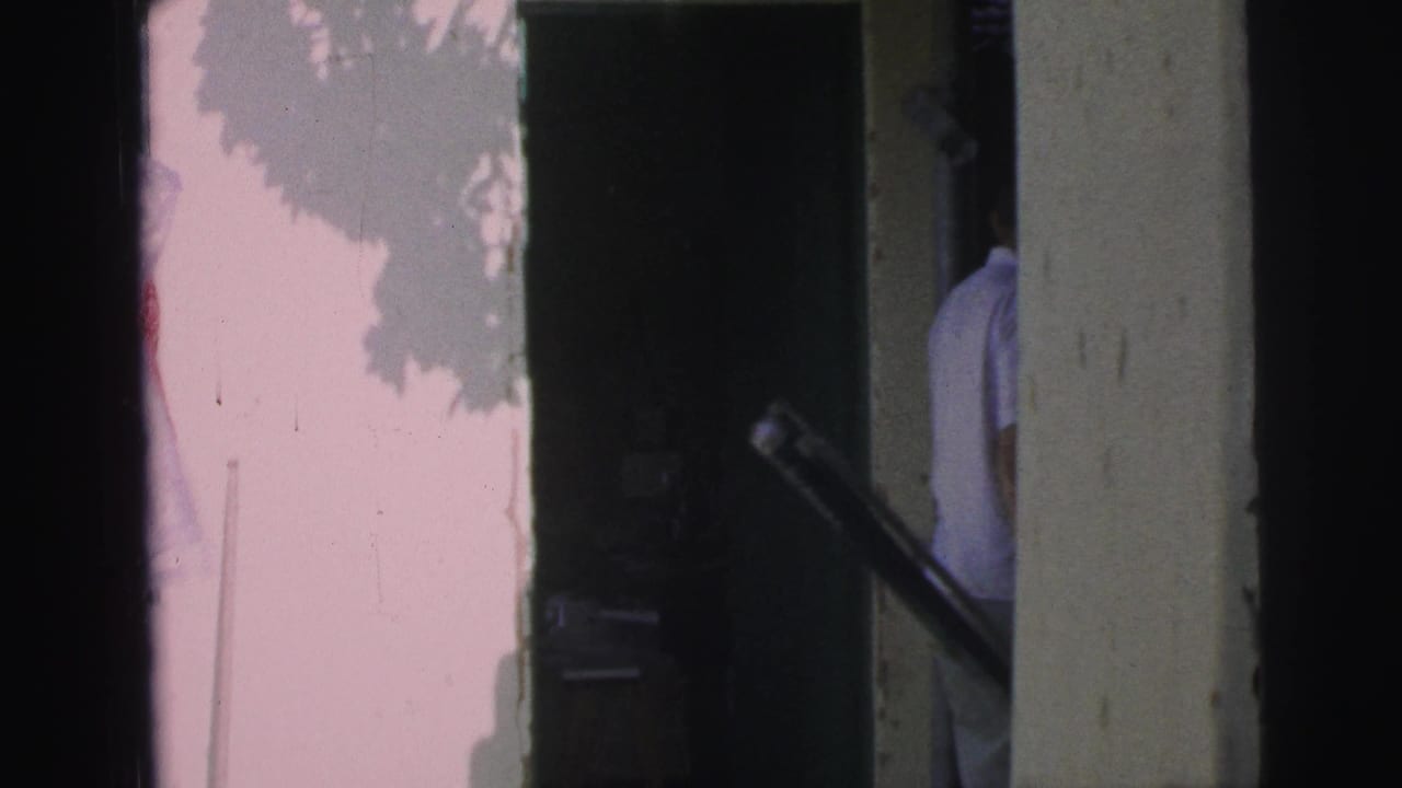 1967 Brazil home-movie frame showing a person partly visible near a dark doorway on a pale residential exterior.