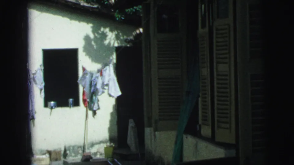 1967 Brazil 8mm frame of a sunlit clothesline area bordered by dark shutters and a shaded passage.
