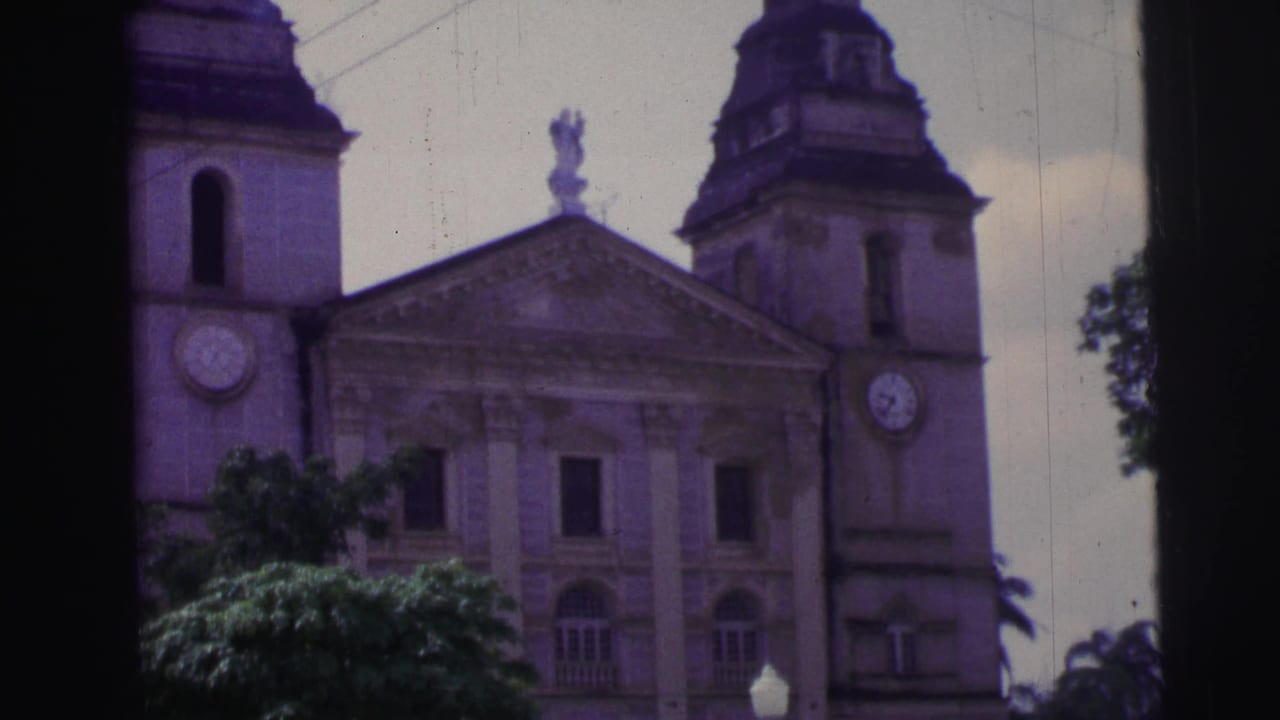 1967 Brazil 8mm frame showing a large white and grey church facade with clock towers, trees, and soft faded color.