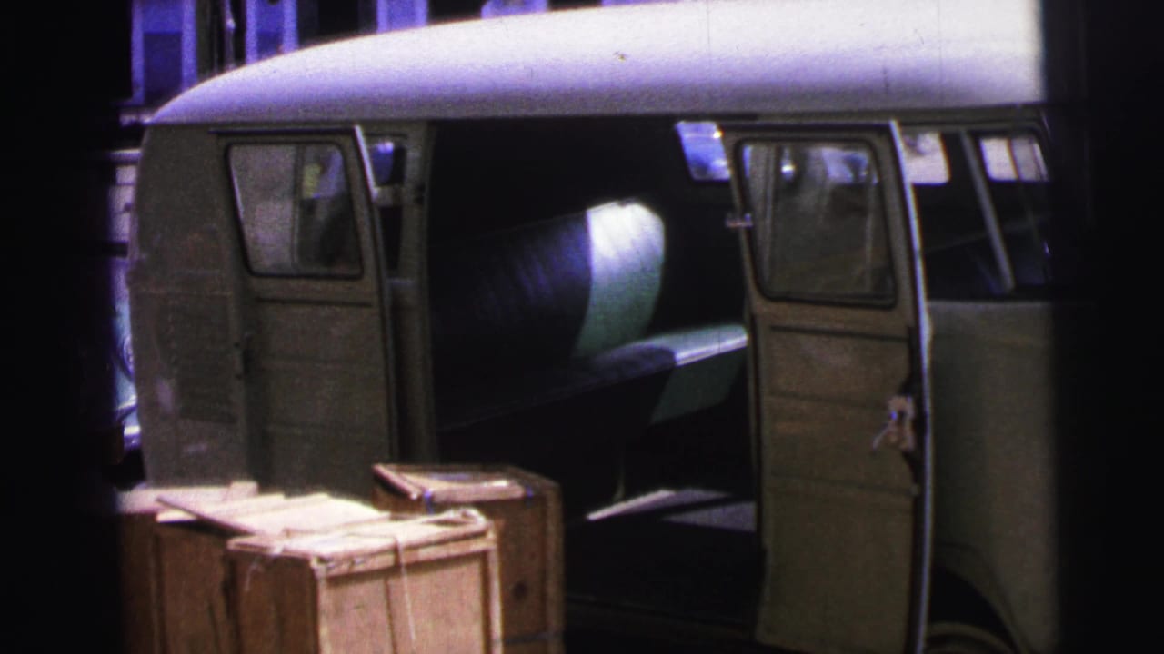 Open classic van beside wooden crates at a dockside location.