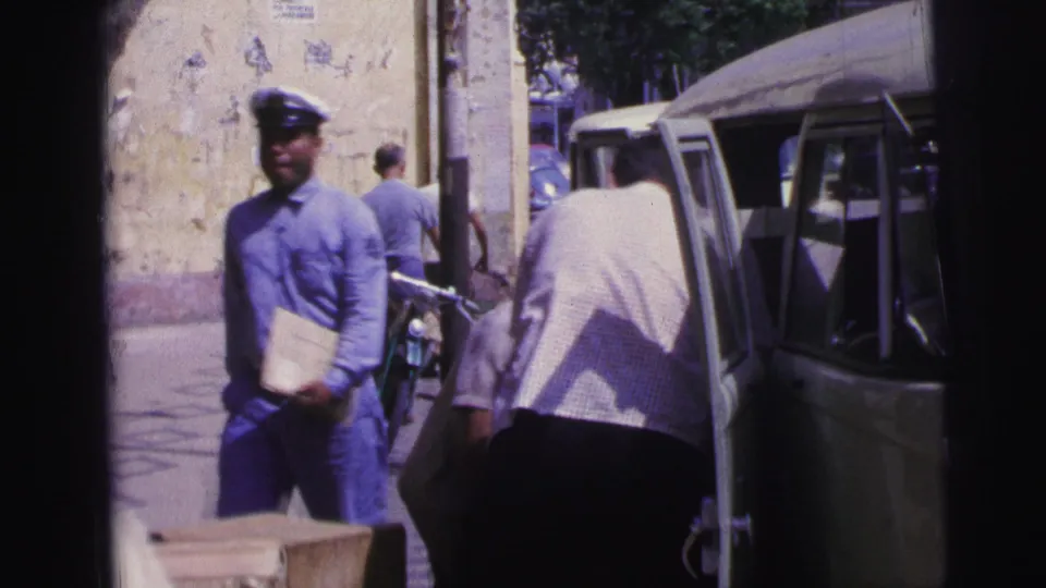 1967 Brazil street frame with a uniformed man, a person unloading near a van, and a bicycle in the background.
