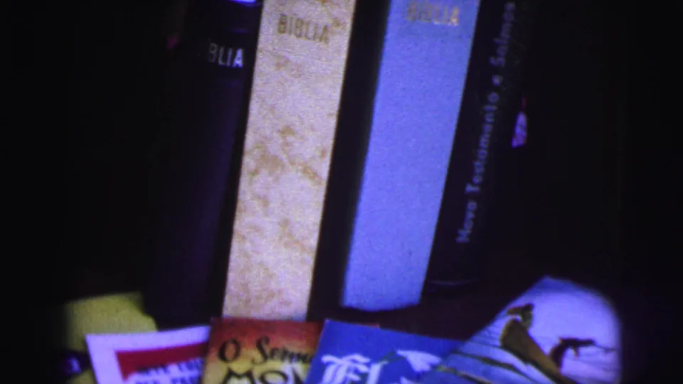 Dim 8mm close-up of Portuguese Bible spines and colorful religious booklets, supported by Brazil 1967 clip metadata.