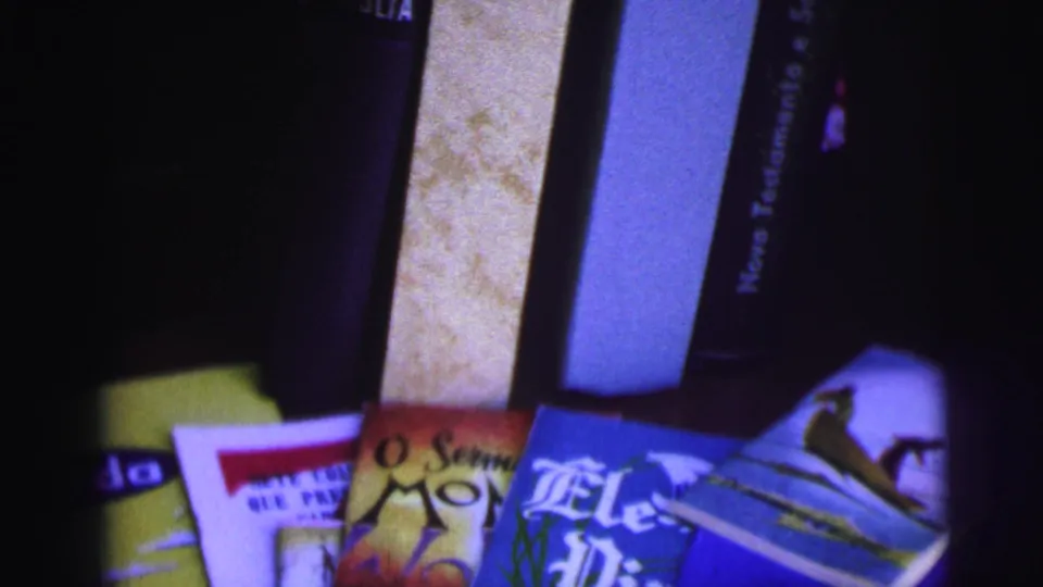 1967 Brazil home-movie frame showing fanned religious pamphlets below upright Portuguese Bible volumes.
