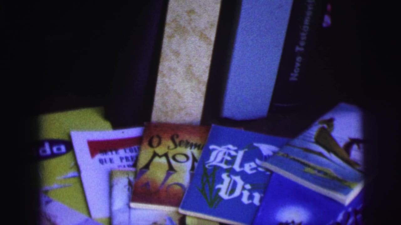 Fanned Portuguese religious pamphlets and small books on a dark surface.