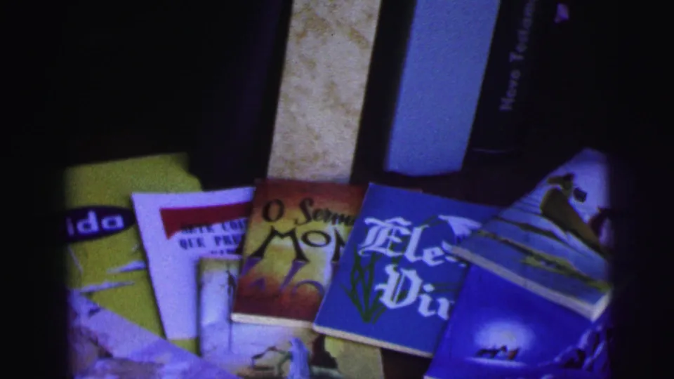 1967 Brazil 8mm close-up of overlapping Portuguese religious pamphlets, including visible title fragments and illustrated covers.