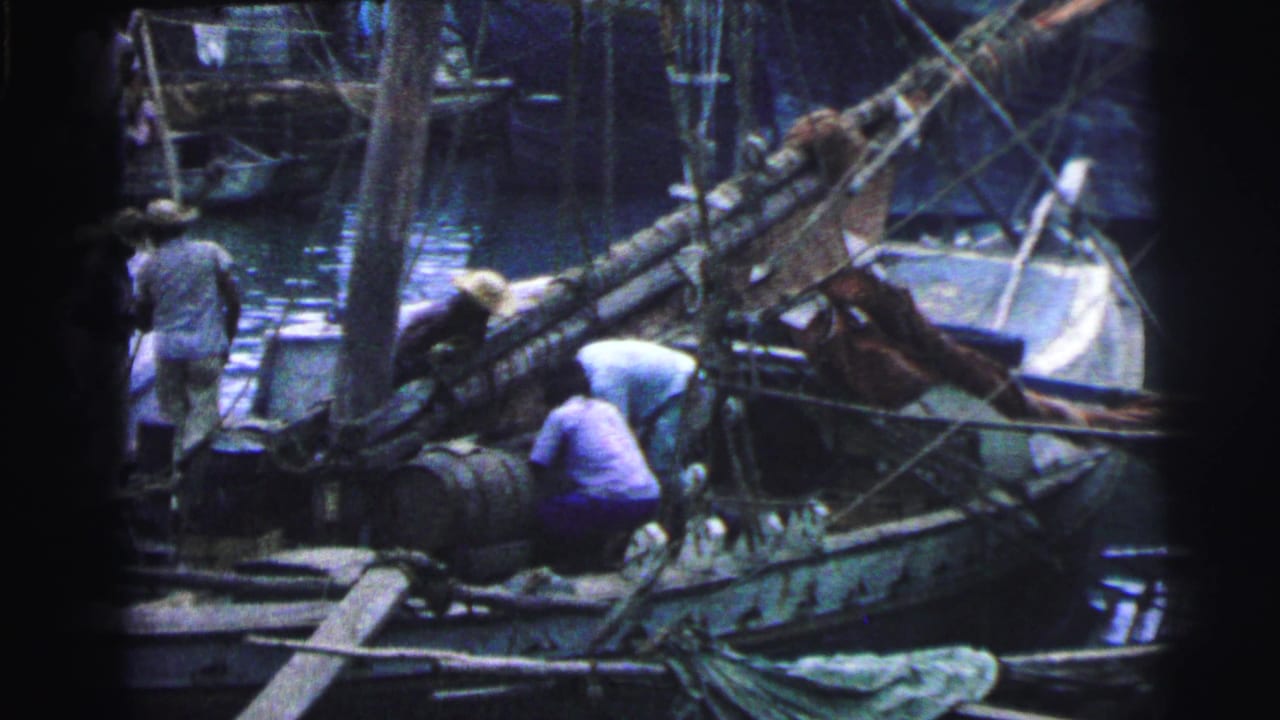 Workers prepare a wooden fishing boat beside barrels, ropes, masts, and harbor water.