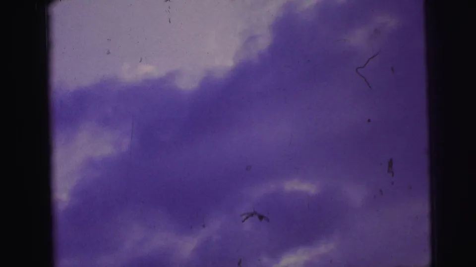 Brazil 1967 8mm frame showing darker purple cloud shapes, a pale sky area, vertical divider, dust, and film abrasion.