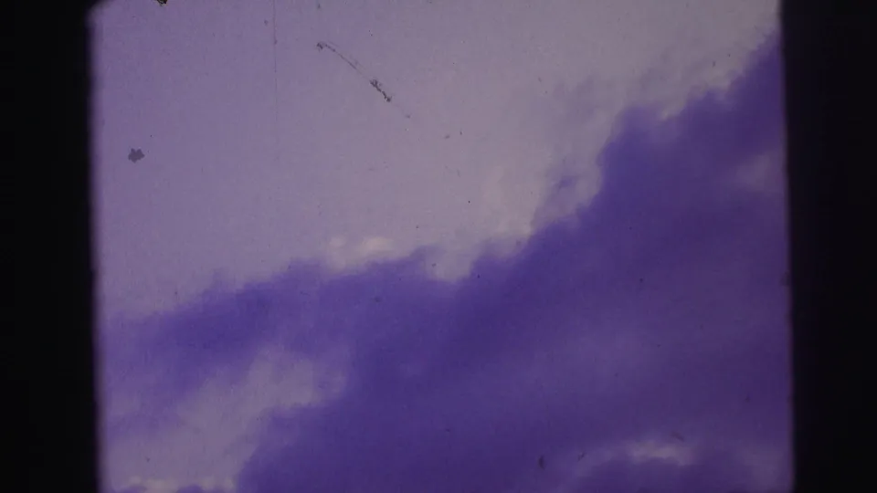 Brazil 1967 8mm frame with violet cloud mass, pale sky opening, dark edge borders, dust, and visible scratches.
